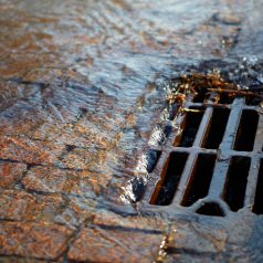 Melted water flows down through the manhole cover on a sunny spring day